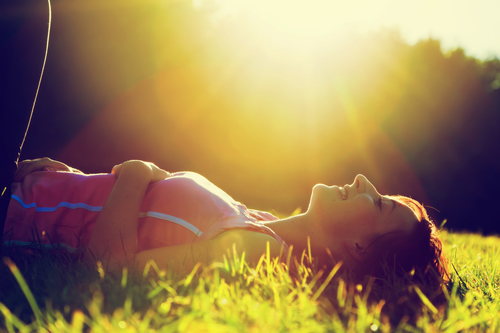 Young pretty woman lying on the grass at summer sunset