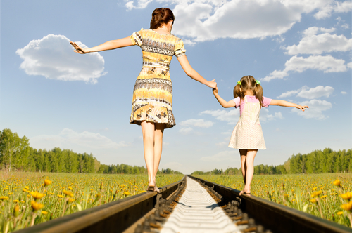 woman walking balanced on the train tracks