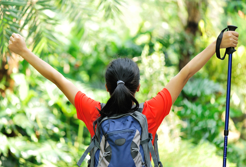 Woman with Hiking Pole and Backpack Celebrating