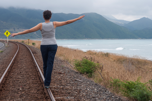 woman walking balanced on the train tracks