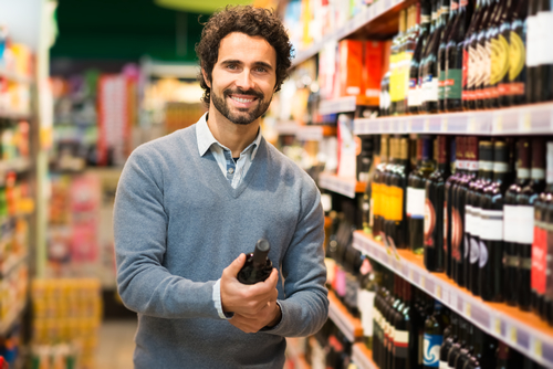Man in a supermarket choosing a wine bottle